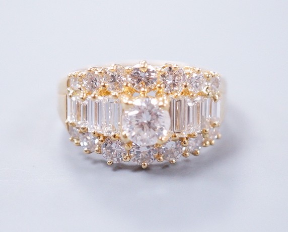A modern 18ct gold and graduated round and baguette cut diamond set three row cluster ring, size M, gross weight 7.4 grams